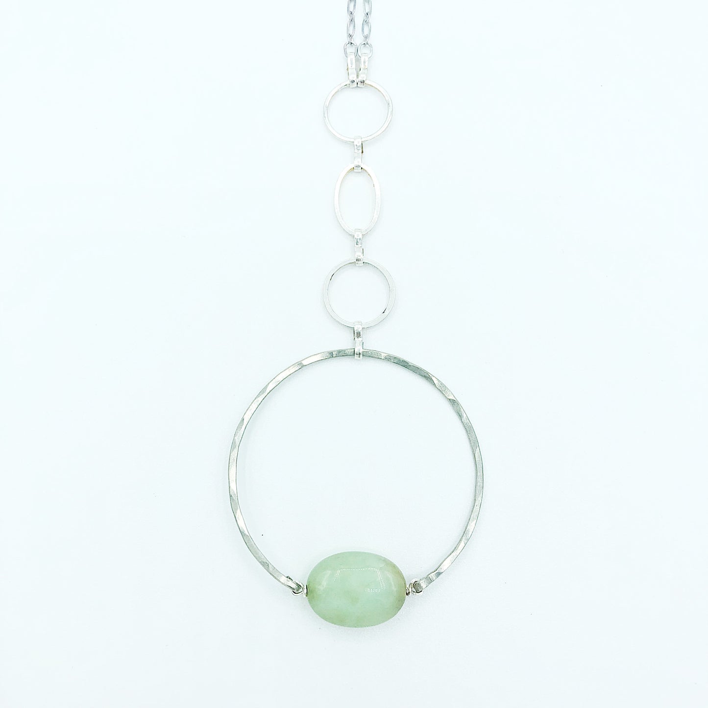 close up of the Apogee Necklace by Third & Co. Studio; light green and brown Chrysophase flat oval, vintage silver circle & oval chain, silver plated nickel-free chain, hammered German silver nickel circle, shown against a white backdrop