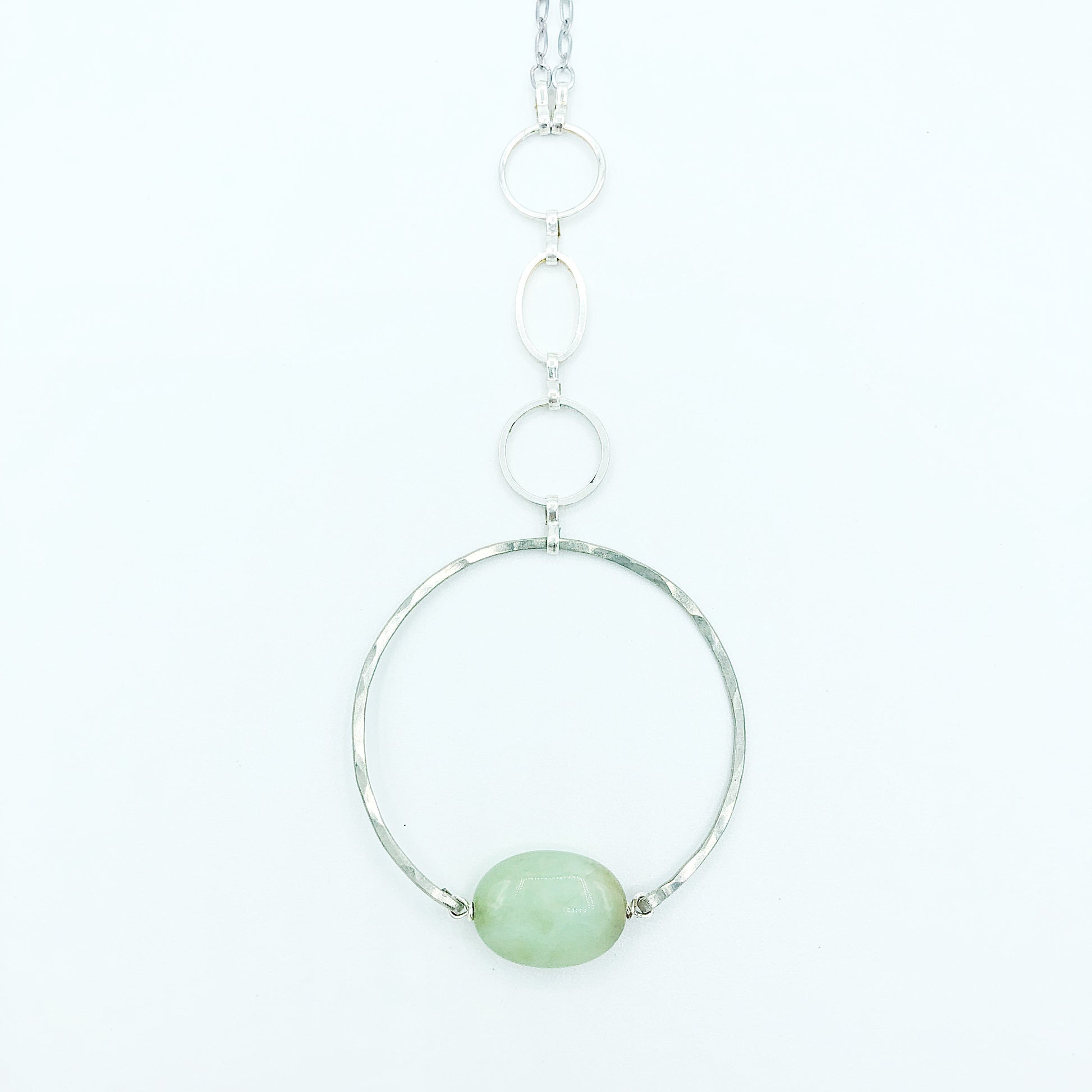 close up of the Apogee Necklace by Third & Co. Studio; light green and brown Chrysophase flat oval, vintage silver circle & oval chain, silver plated nickel-free chain, hammered German silver nickel circle, shown against a white backdrop