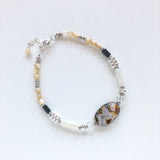 Bracelet with blue green black abalone, white and cream yellow and tan mother of pearl, gray hematite, clear faceted quartz, sterling silver beads and chain adjustable length on white background