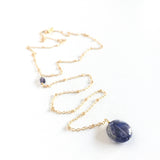 Andromeda Necklace by Third & Co. Studio; faceted and round blue Iolite, gold plated satellite chain lariat necklace with lobster claw clasp, shown against a white background