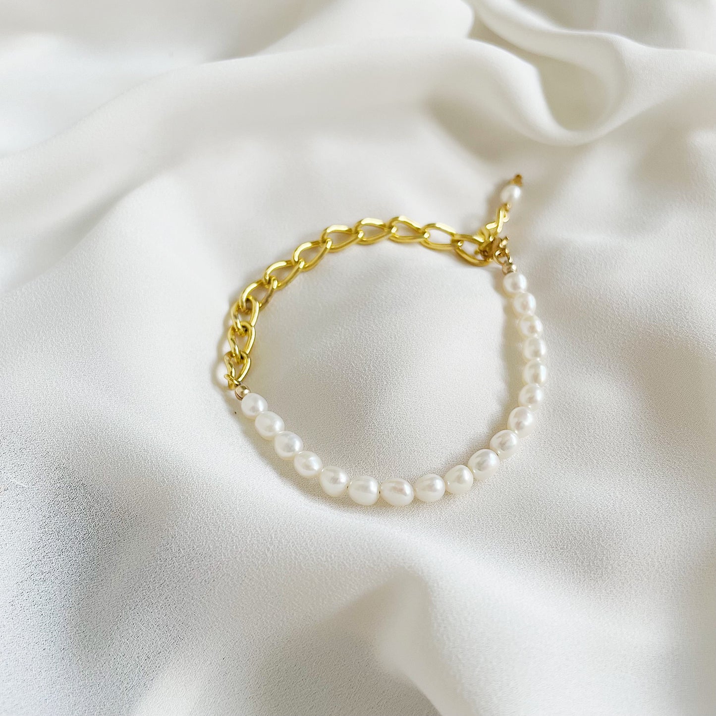 Aletta Bracelet from Third & Co. Studio with white fresh water pearl, gold plated vintage chain with adjustable length against a creamy silky fabric background