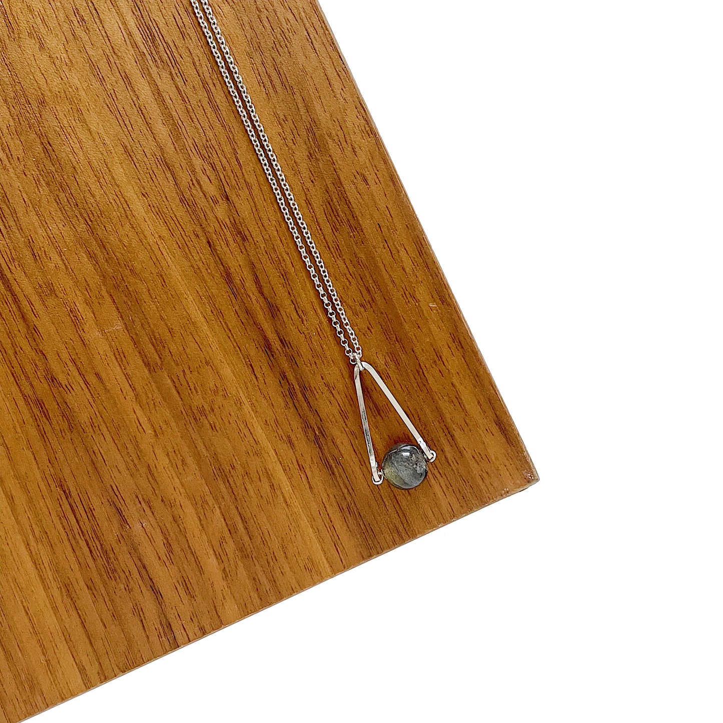 Labradorite round in green gray with flashing blue, sterling silver elongated triangle shape, sterling silver chain short necklace on wood and white backround