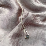 Labradorite round in green gray with flashing blue, sterling silver elongated triangle shape, sterling silver chain short necklace on silky gray fabric background