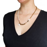 The Aletta Necklace by Third & Co. Studio: fresh water pearl, vintage gold-toned chain, mother of pearl and labradorite, create this adjustable length, wear-two-ways necklace. Can also be worn as a bracelet by wrapping around the wrist. Necklace shown on a model wearing a black v-neck top, against a white background