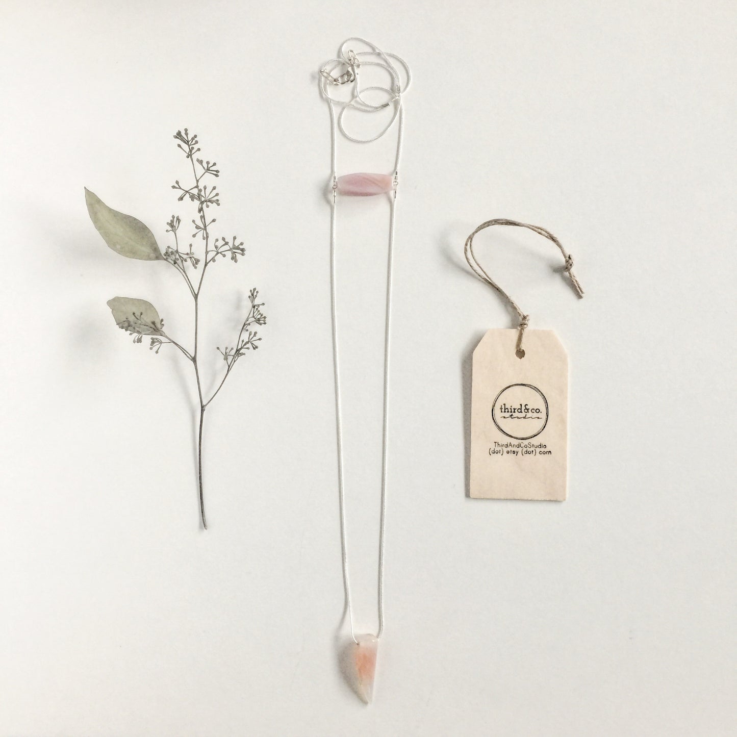 Binary Necklace by Third & Co. Studio: Agate "tooth" and tube shape in cream peach mauve orange, minimalist design with Sterling Silver snake chain lariat style long length, shown on a white background with dried florals