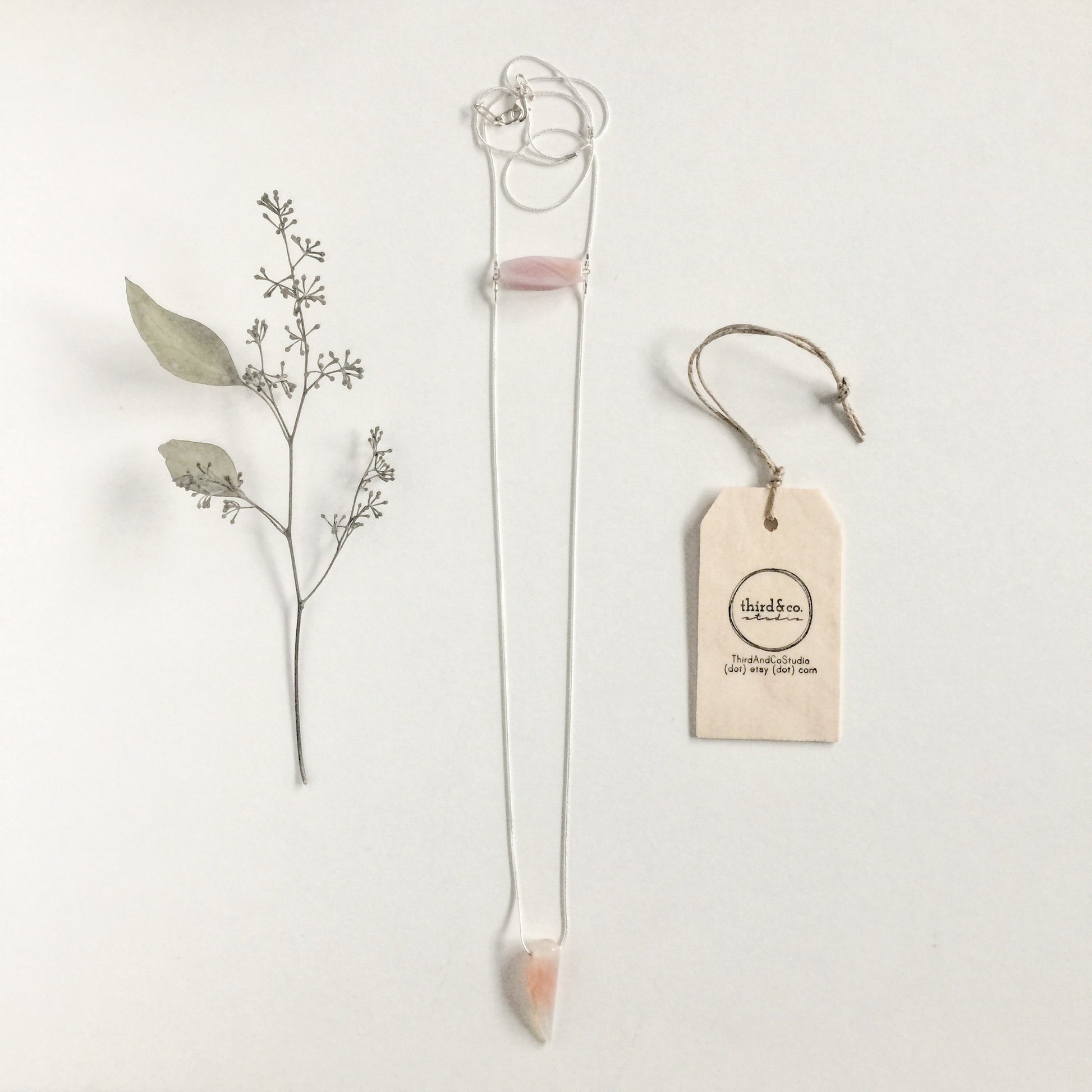Binary Necklace by Third & Co. Studio: Agate "tooth" and tube shape in cream peach mauve orange, minimalist design with Sterling Silver snake chain lariat style long length, shown on a white background with dried florals