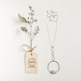 Apogee Necklace by Third & Co. Studio; light green and brown Chrysophase flat oval, vintage silver circle & oval chain, silver plated nickel-free chain, hammered German silver nickel circle, pictured against a white backdrop with dried greenery