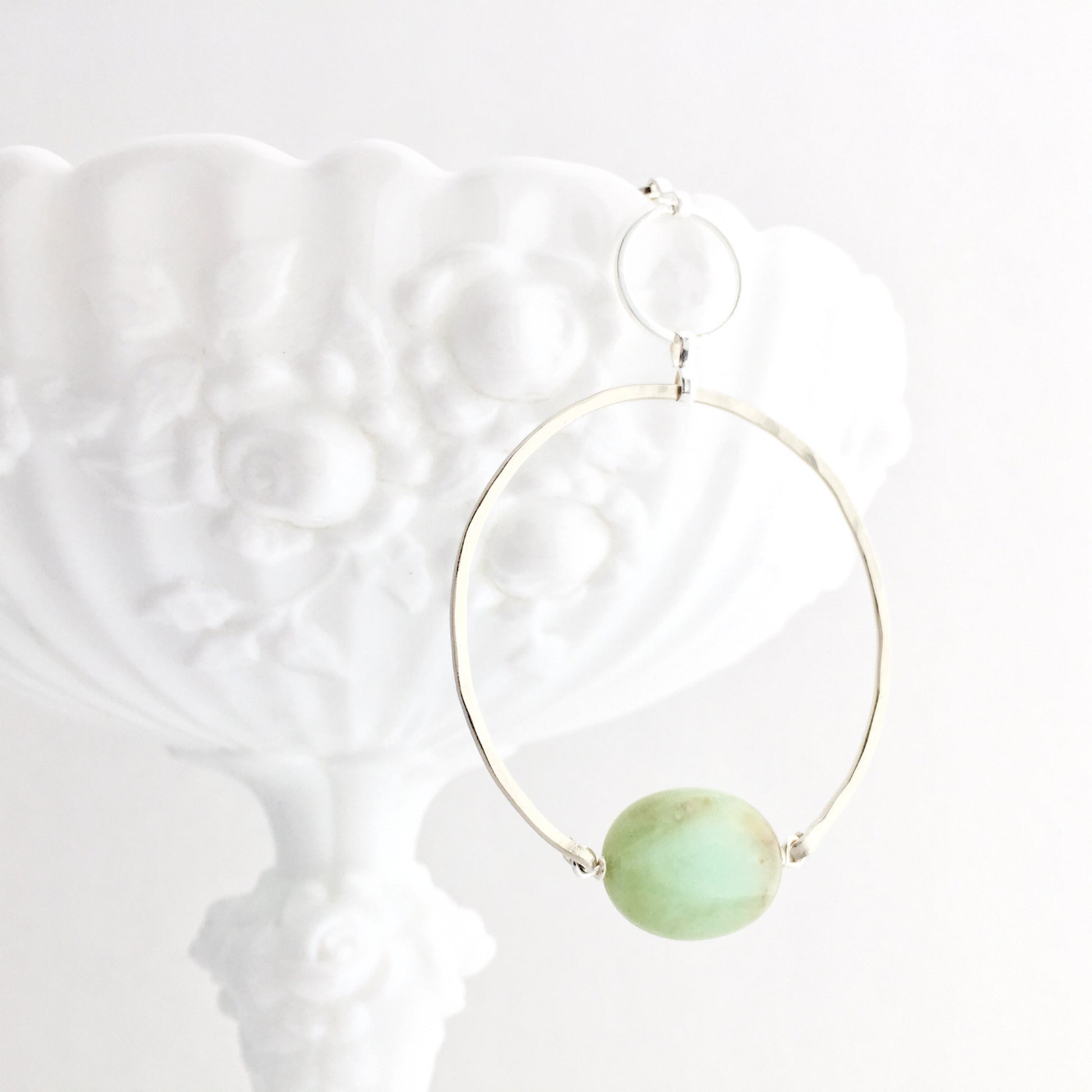 Apogee Necklace by Third & Co. Studio; light green and brown Chrysophase flat oval, vintage silver circle & oval chain, silver plated nickel-free chain, hammered German silver nickel circle, shown closeup draped on a white dish and white background