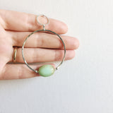 a model holding the Apogee Necklace by Third & Co. Studio; light green and brown Chrysophase flat oval, vintage silver circle & oval chain, silver plated nickel-free chain, hammered German silver nickel circle, chrysophase shown close up