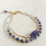 Andromeda Bracelet by Third & Co. Studio; faceted blue Iolite, round clear and blue Quartz and Iolite, gold plated satellite chain adjustable length bracelet with lobster claw clasp, shown against a beige background