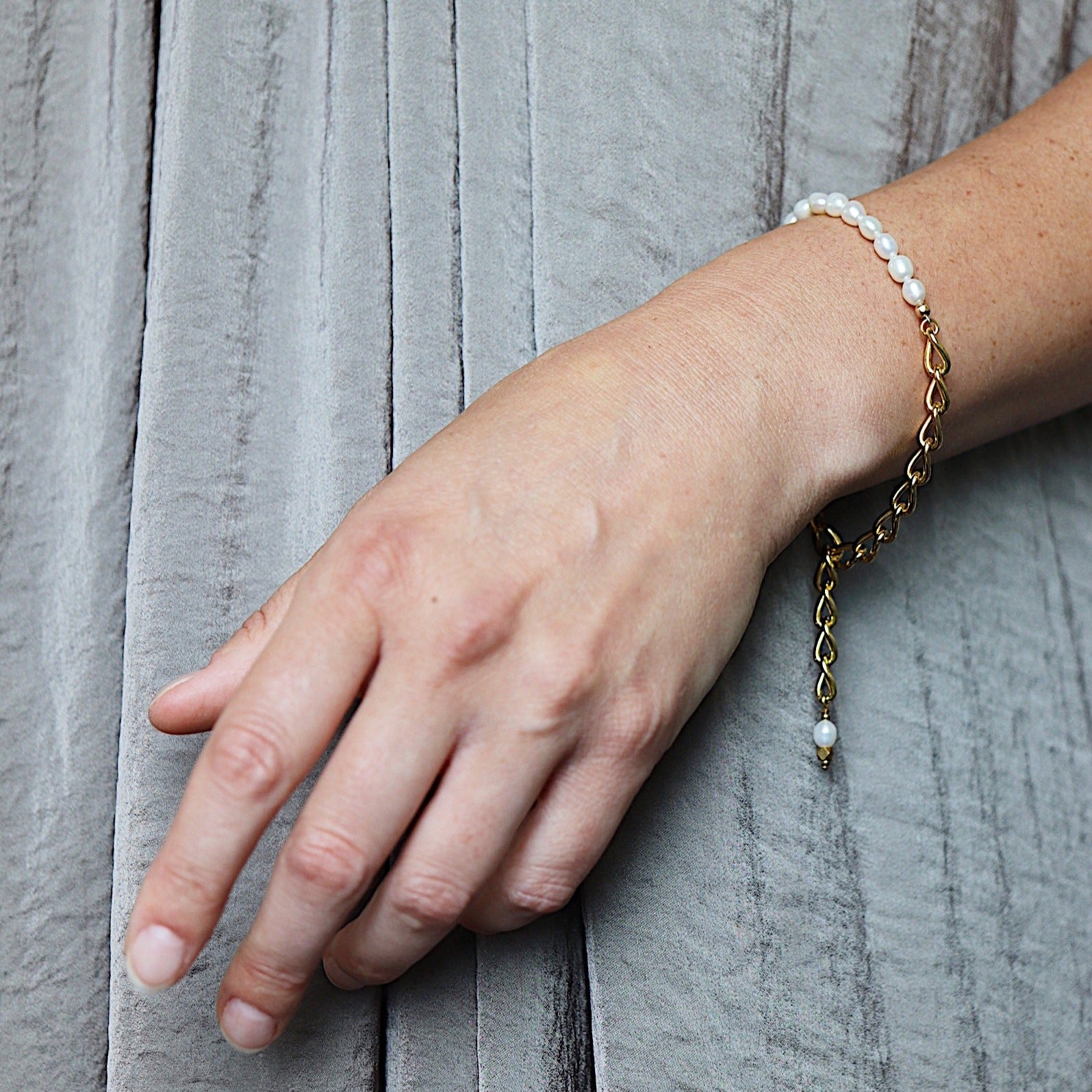 a model wearing the Aletta Bracelet from Third & Co. Studio with white fresh water pearl, gold plated vintage chain with adjustable length