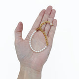 a hand holding the Aletta Bracelet from Third & Co. Studio with white fresh water pearl, gold plated vintage chain with adjustable length against a white background