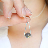 model holding a Labradorite round in green gray with flashing blue, sterling silver elongated triangle shape, sterling silver chain short necklace