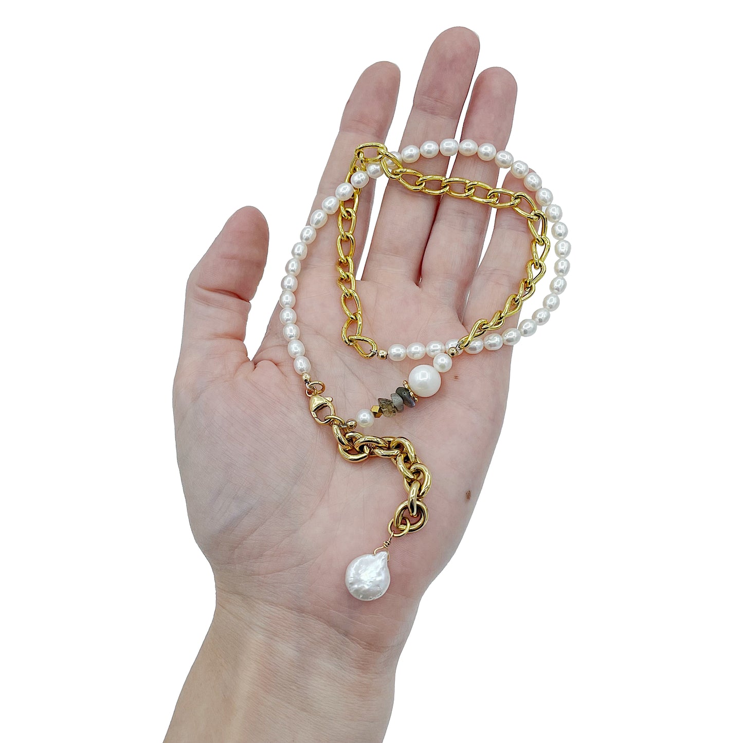 The Aletta Necklace by Third & Co. Studio: fresh water pearl, vintage gold-toned chain, mother of pearl and labradorite, create this adjustable length, wear-two-ways necklace. Can also be worn as a bracelet by wrapping around the wrist. Necklace held in model's hand against a white background