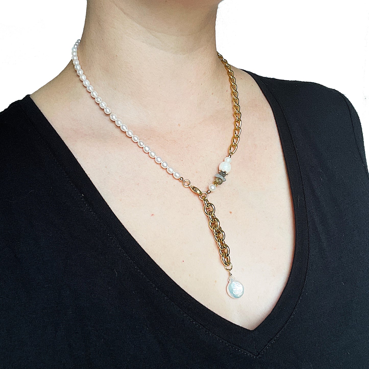 The Aletta Necklace by Third & Co. Studio: fresh water pearl, vintage gold-toned chain, mother of pearl and labradorite, create this adjustable length, wear-two-ways necklace. Can also be worn as a bracelet by wrapping around the wrist. Necklace shown on a model wearing a black v-neck top, at the shortest adjustable lariat length, against a white background