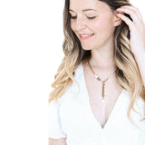 The Aletta Necklace by Third & Co. Studio: fresh water pearl, vintage gold-toned chain, mother of pearl and labradorite, create this adjustable length, wear-two-ways necklace. Can also be worn as a bracelet by wrapping around the wrist. Necklace shown on a model wearing a white top, with the lariat length, against a white background