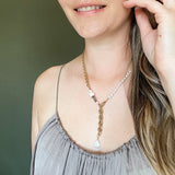 The Aletta Necklace by Third & Co. Studio: fresh water pearl, vintage gold-toned chain, mother of pearl and labradorite, create this adjustable length, wear-two-ways necklace. Can also be worn as a bracelet by wrapping around the wrist. Necklace shown on a model at the shortest adjustable lariat length, against a green background